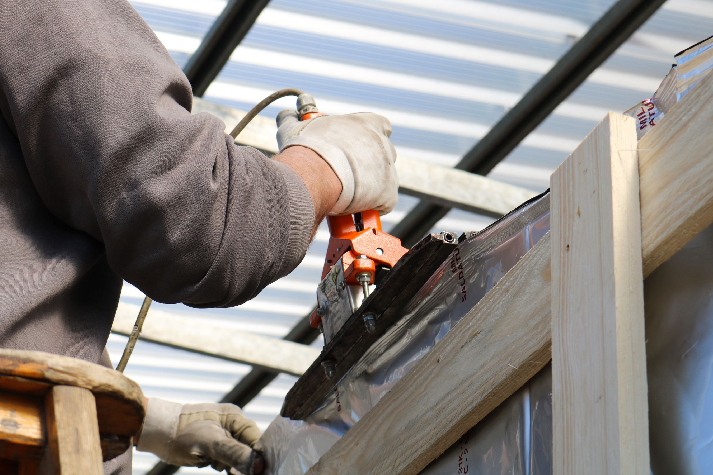 A construction worker using a power tool on a residential building exterior